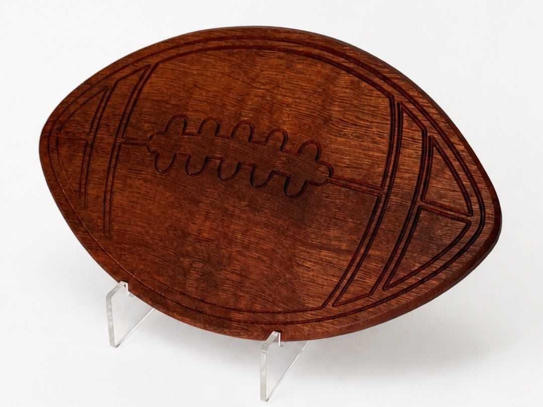Football-shaped wooden charcuterie board with engraved laces, styled flat on a clean white background.